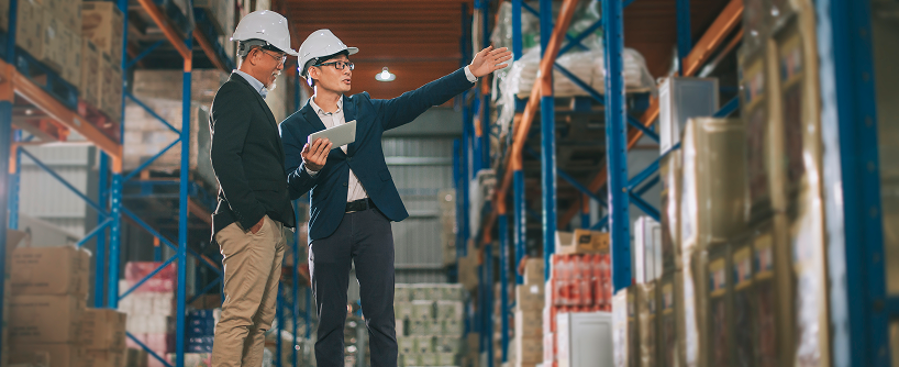 Warehouse management team discussing supply chain operations on warehouse floor